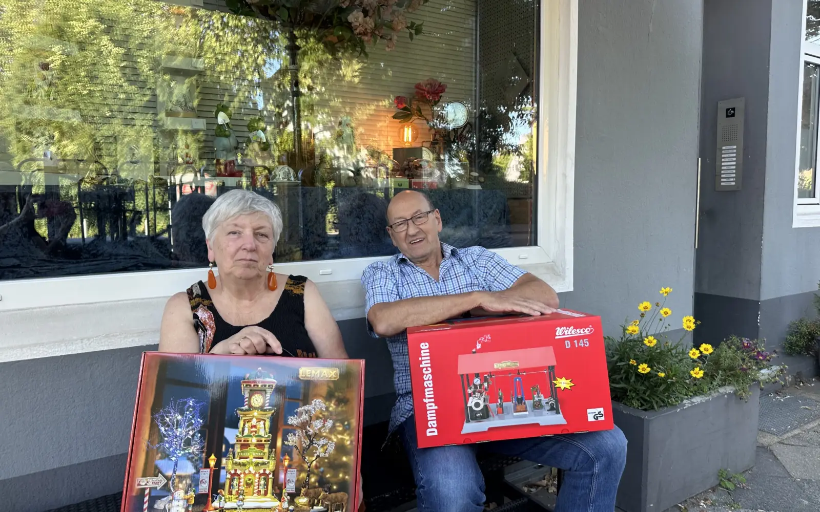 Ramona und Ludwig Krämer führen Krämers Kiosk am Niederkasseler Kirchweg seit 42 Jahren und zeigen zwei Schätze aus dem Moba Stübchen, ein Lemax-Weihnachtshaus und eine Wilesco-Dampfmaschine.