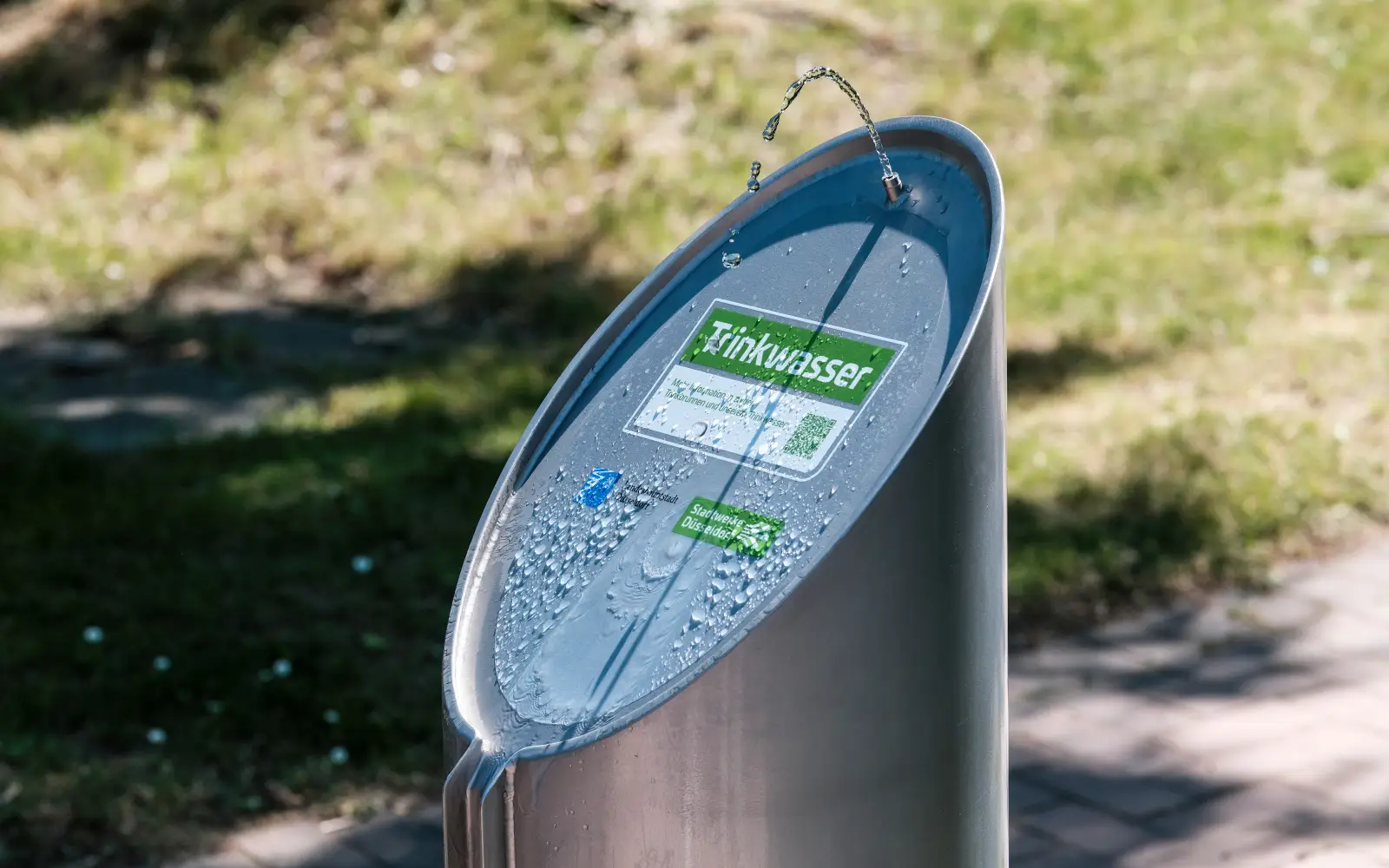 Aus dem neuen Edelstahl-Trinkbrunnen sprudelt frisches Düsseldorfer Trinkwasser. Ein Aufkleber weist auf das kostenlose Angebot der Stadtwerke Düsseldorf hin.